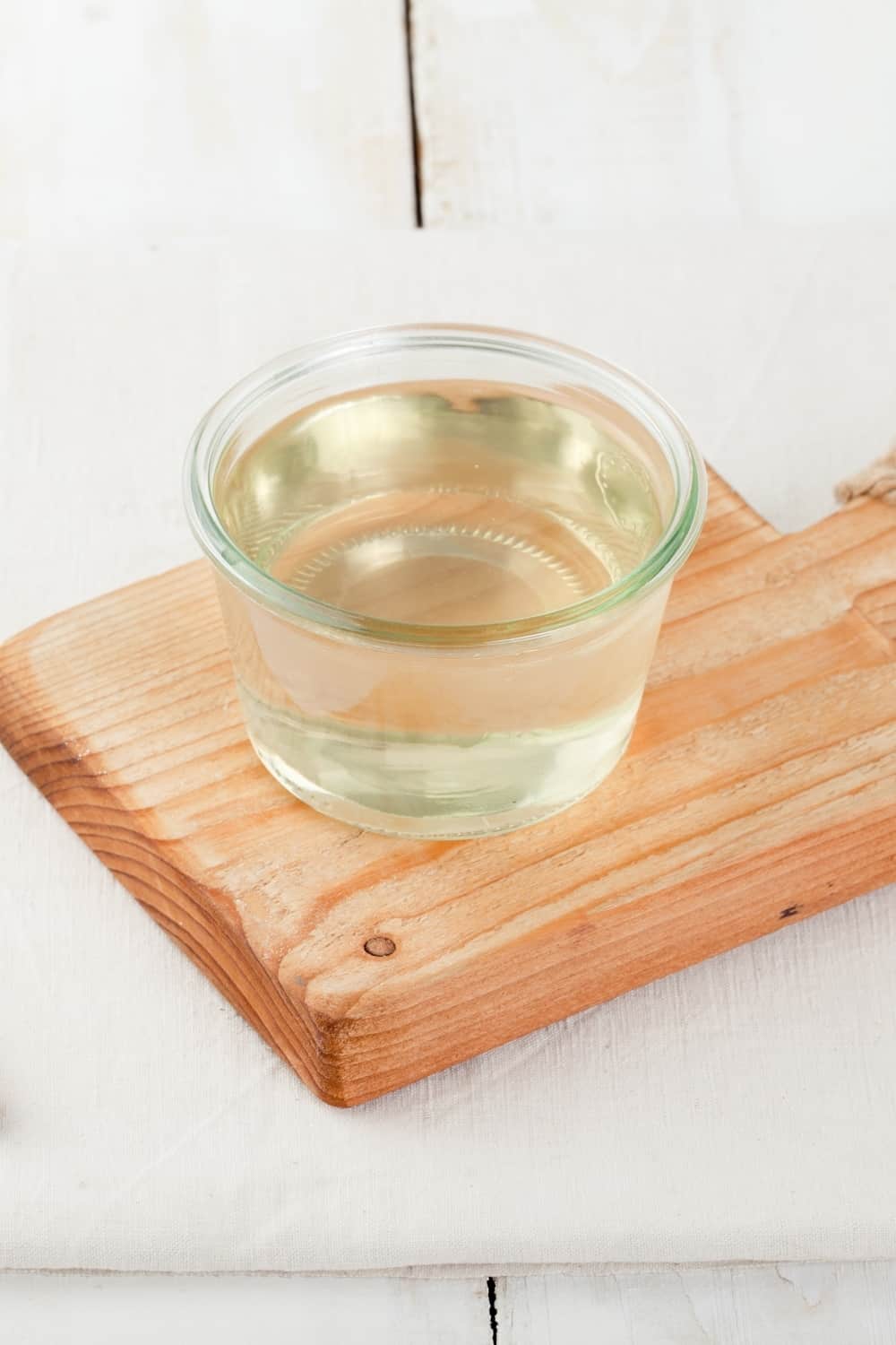 Sugar syrup in a glass bowl on a white wooden background