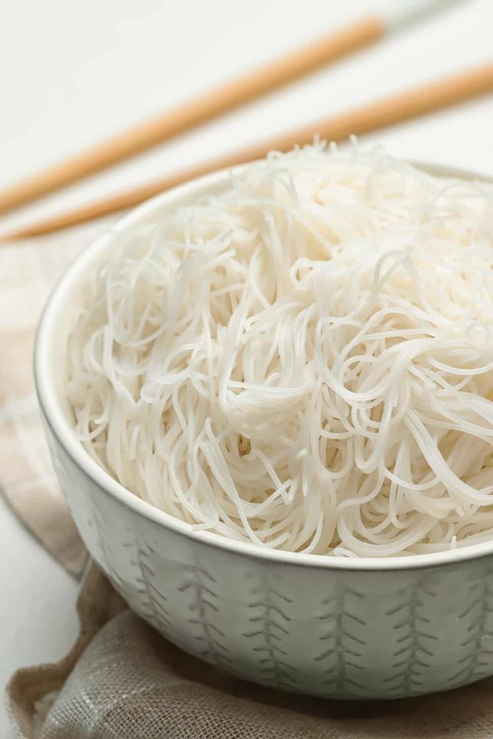 Sabrosos fideos de arroz cocidos sobre mesa blanca