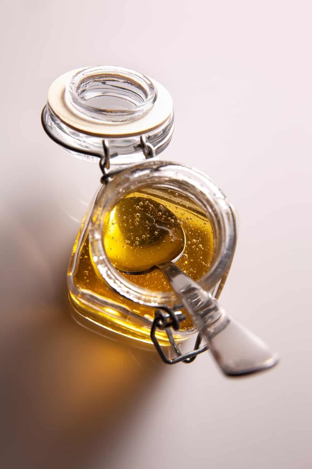 detail of agave syrup in glass jar with spoon inside.