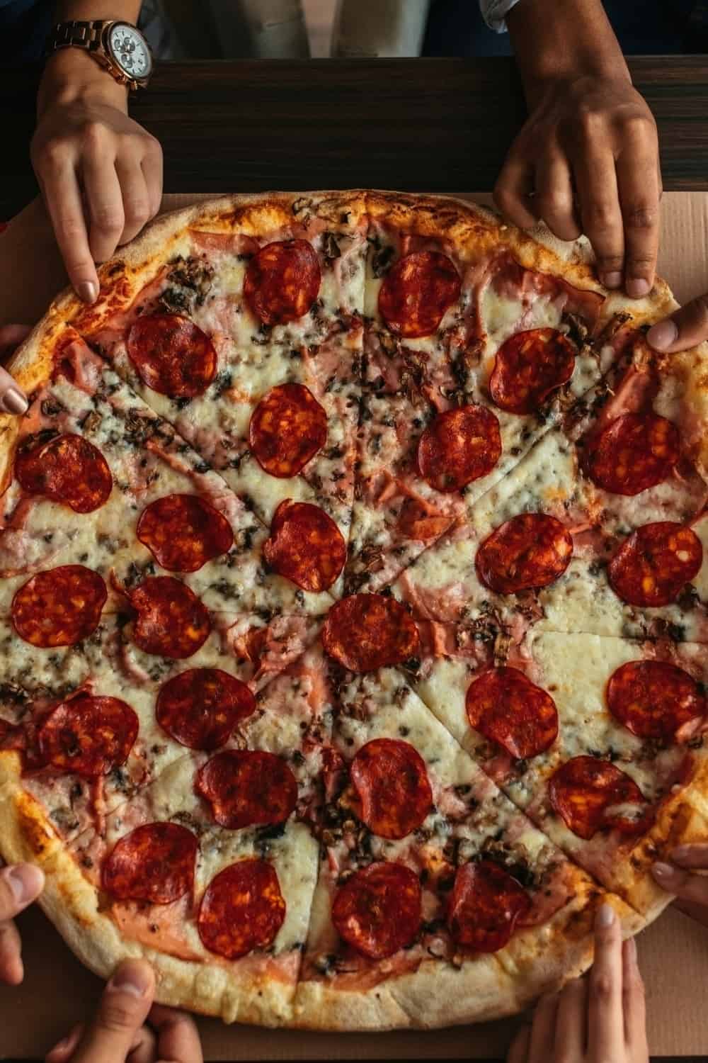 mains prenant un morceau de pizza