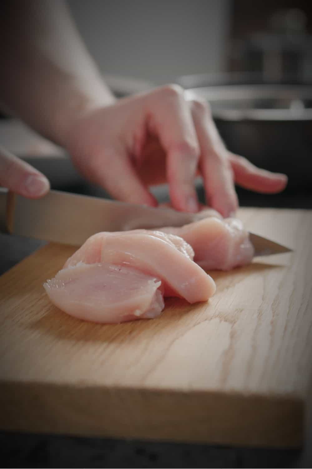 a woman cuts a chicken on a cutting board