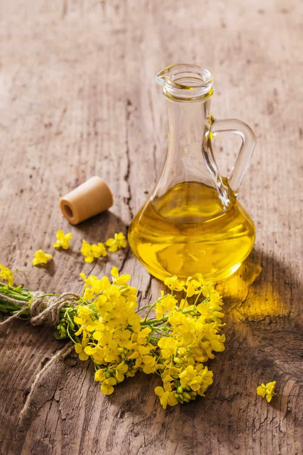 Rapsöl in einer Flasche neben den Blumen