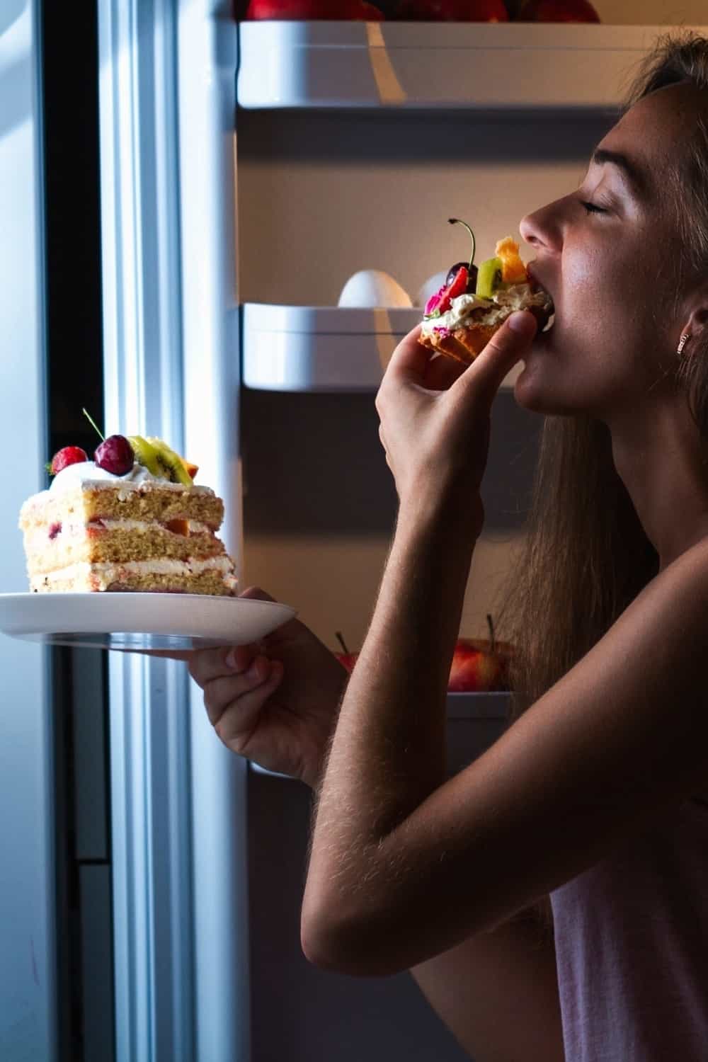 happy girl eating a cake from fridge