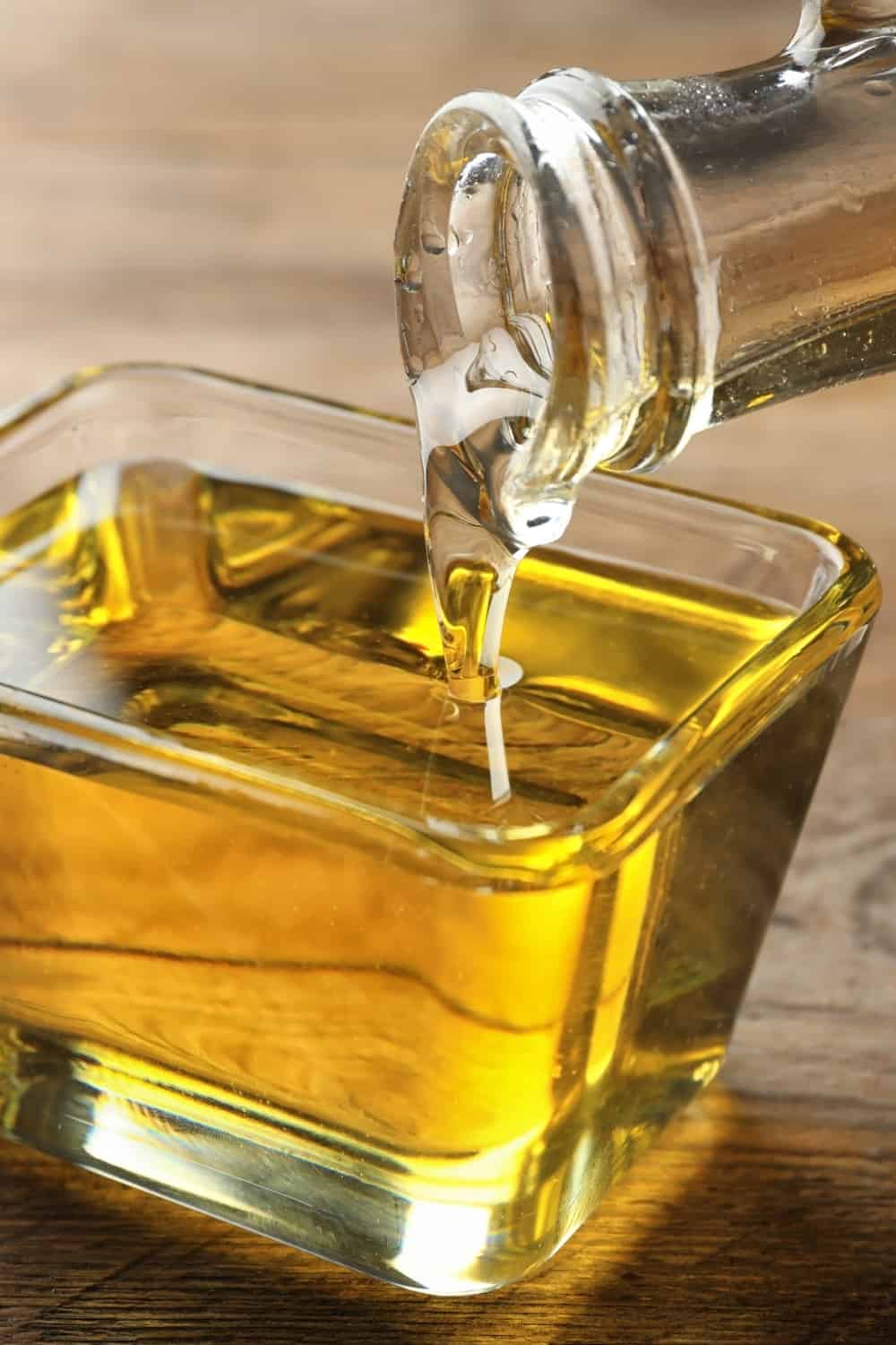 person pouring canola oil in a small container
