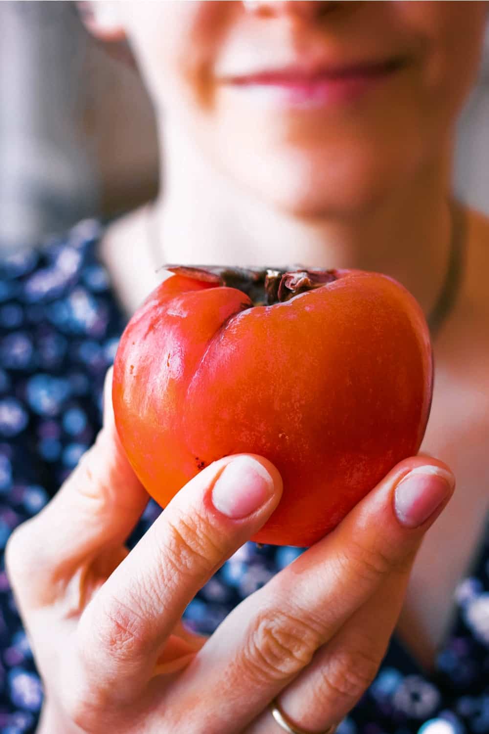 the woman holds a persimmon in her hand