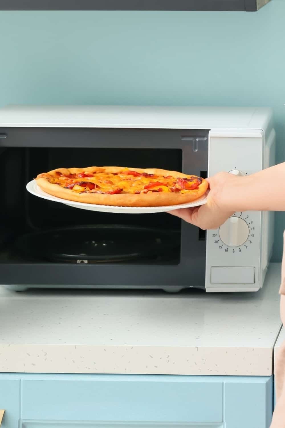 Frau legt Pizza in die Mikrowelle