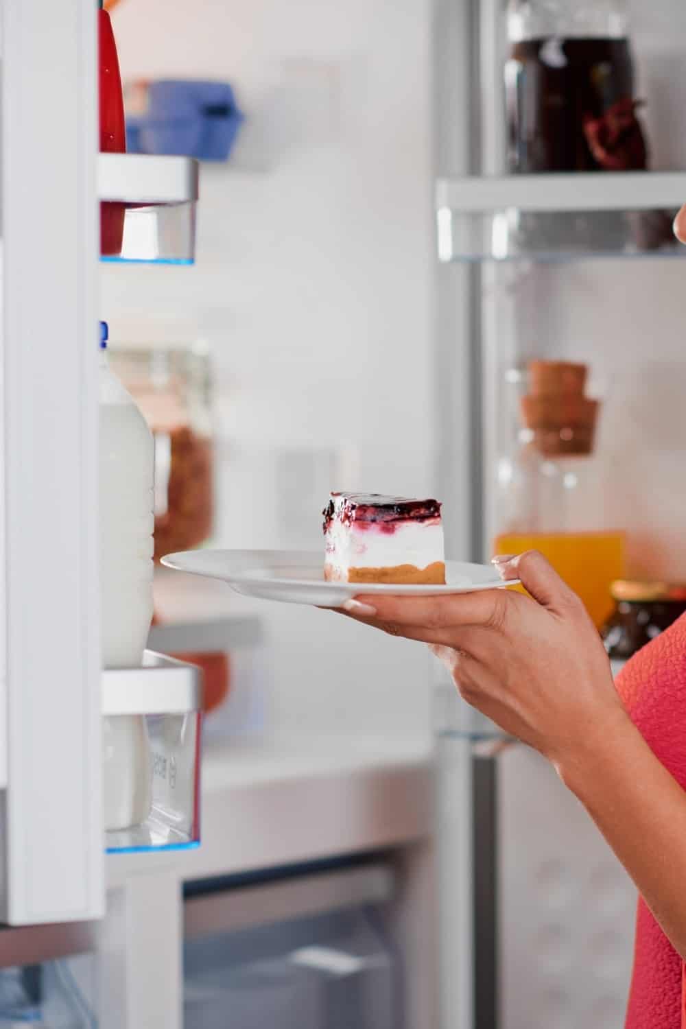 woman taking out a piece of cheesecake from the fridge