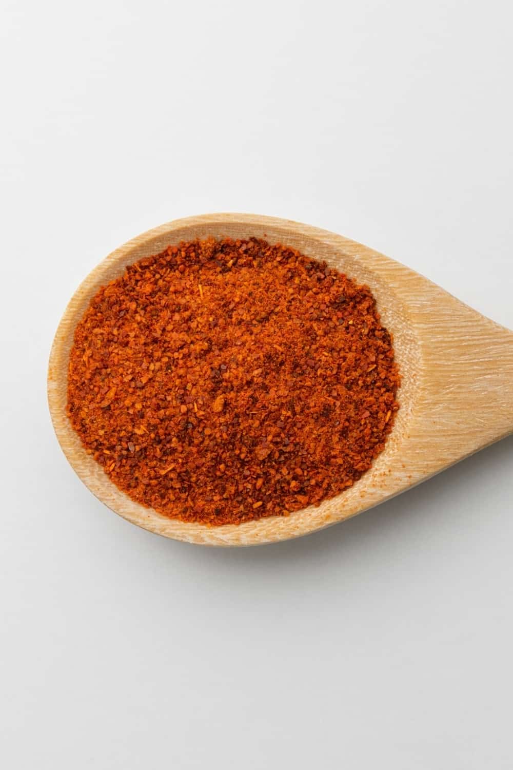 wooden spoon of paprika on white background
