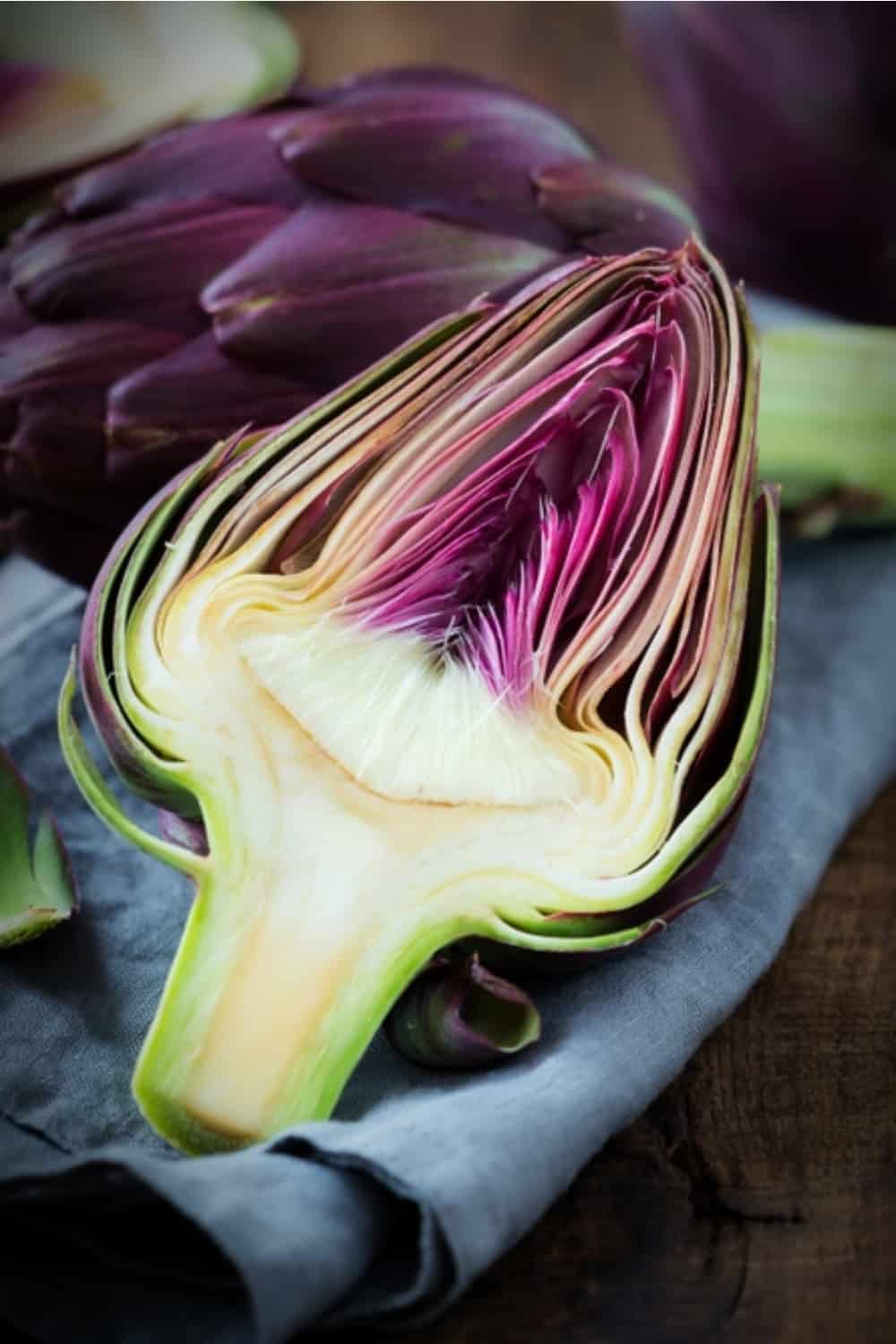 Fresh purple artichokes on dark rustic wooden background