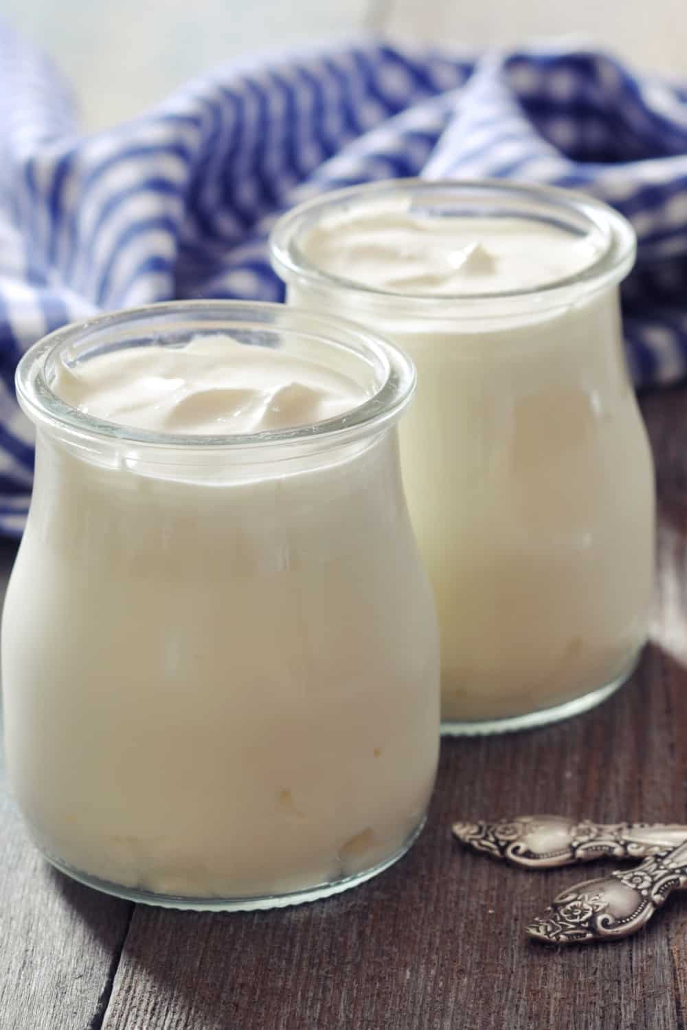 Griechischer Joghurt in einem Glas mit Löffeln auf hölzernem Hintergrund