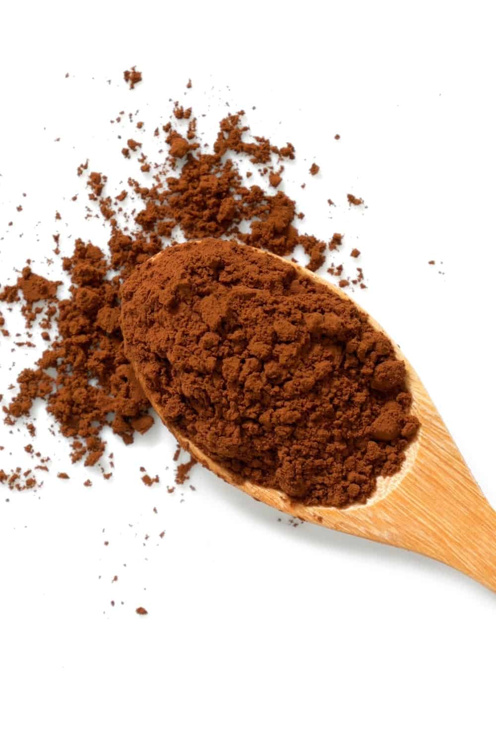 Pile of cocoa powder in wooden spoon isolated on white background