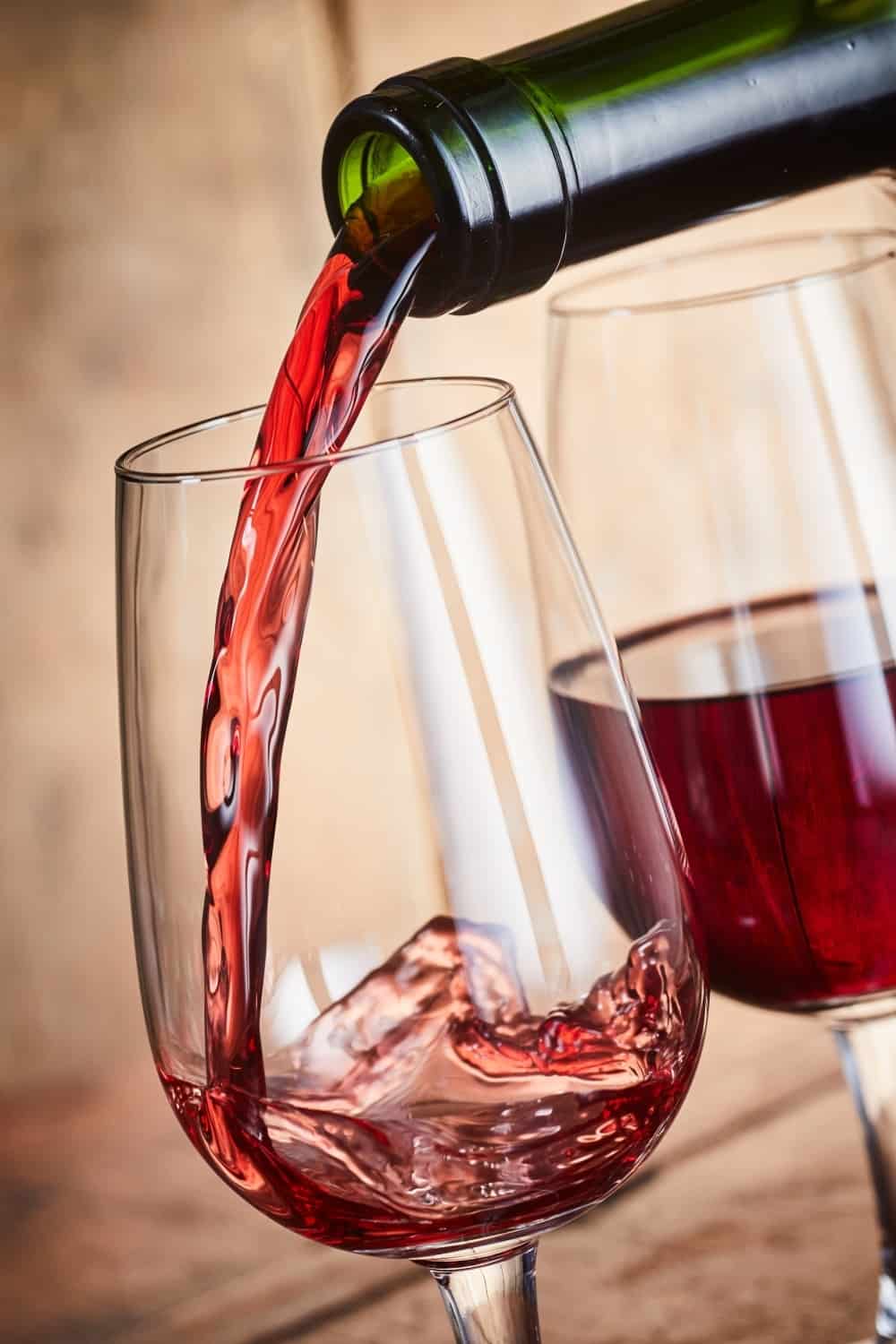 Servir dos copas de vino de Oporto tinto fortificado de una botella