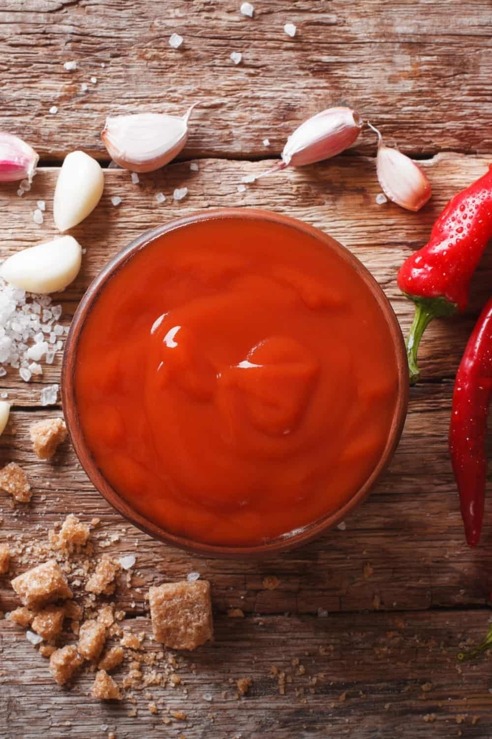 Rote Chilisauce Sriracha mit Zutaten auf dem Tisch