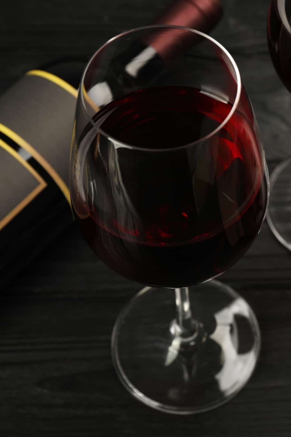 Sabroso vino tinto y chocolate sobre mesa de madera negra