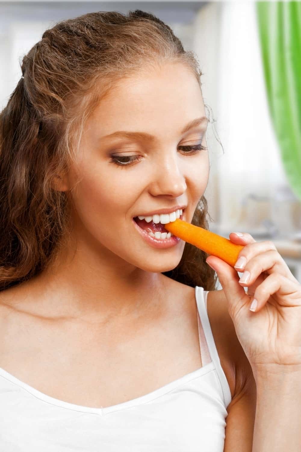 the woman is eating a fresh carrot