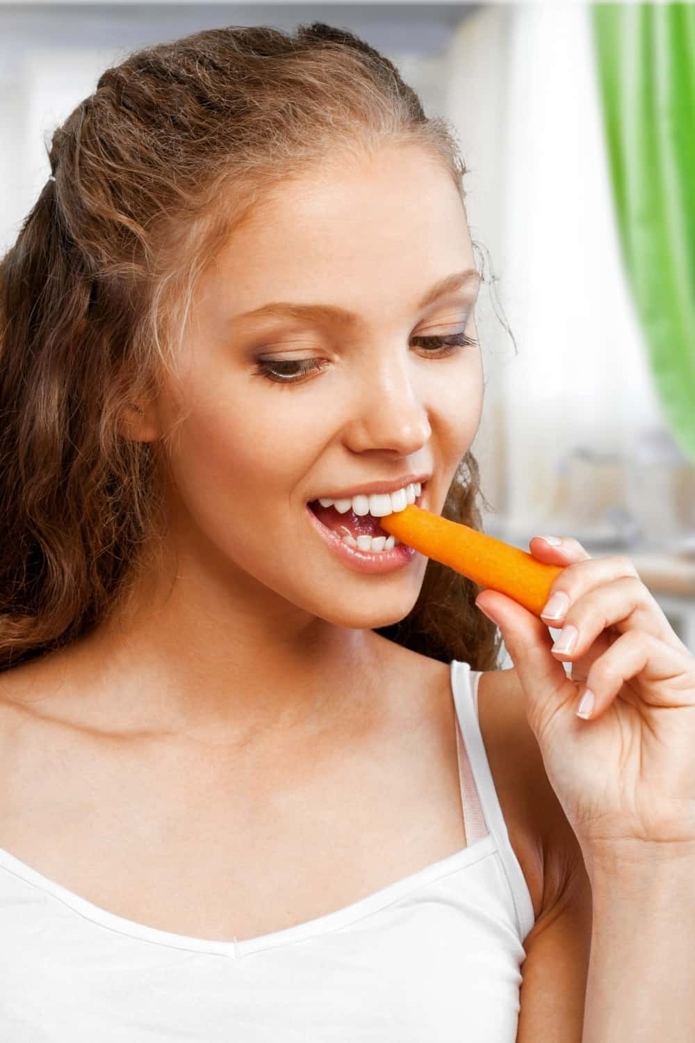 la mujer está comiendo una zanahoria fresca