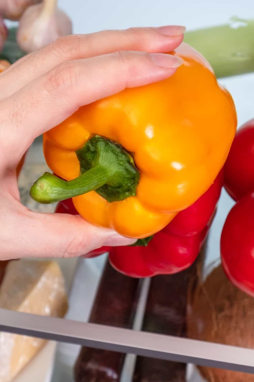 person puts bell pepper in fridge