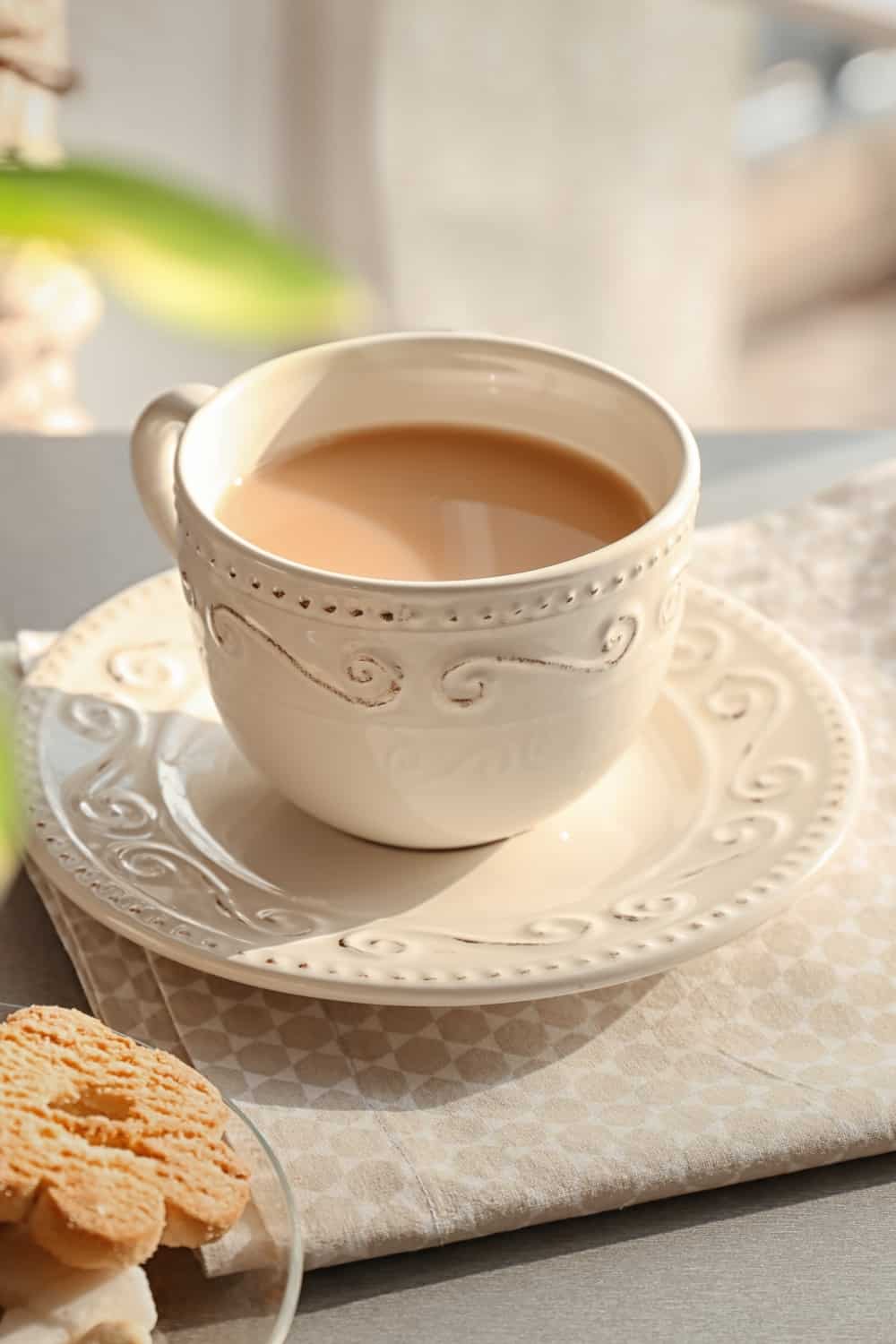 Cup of aromatic tea with milk on table