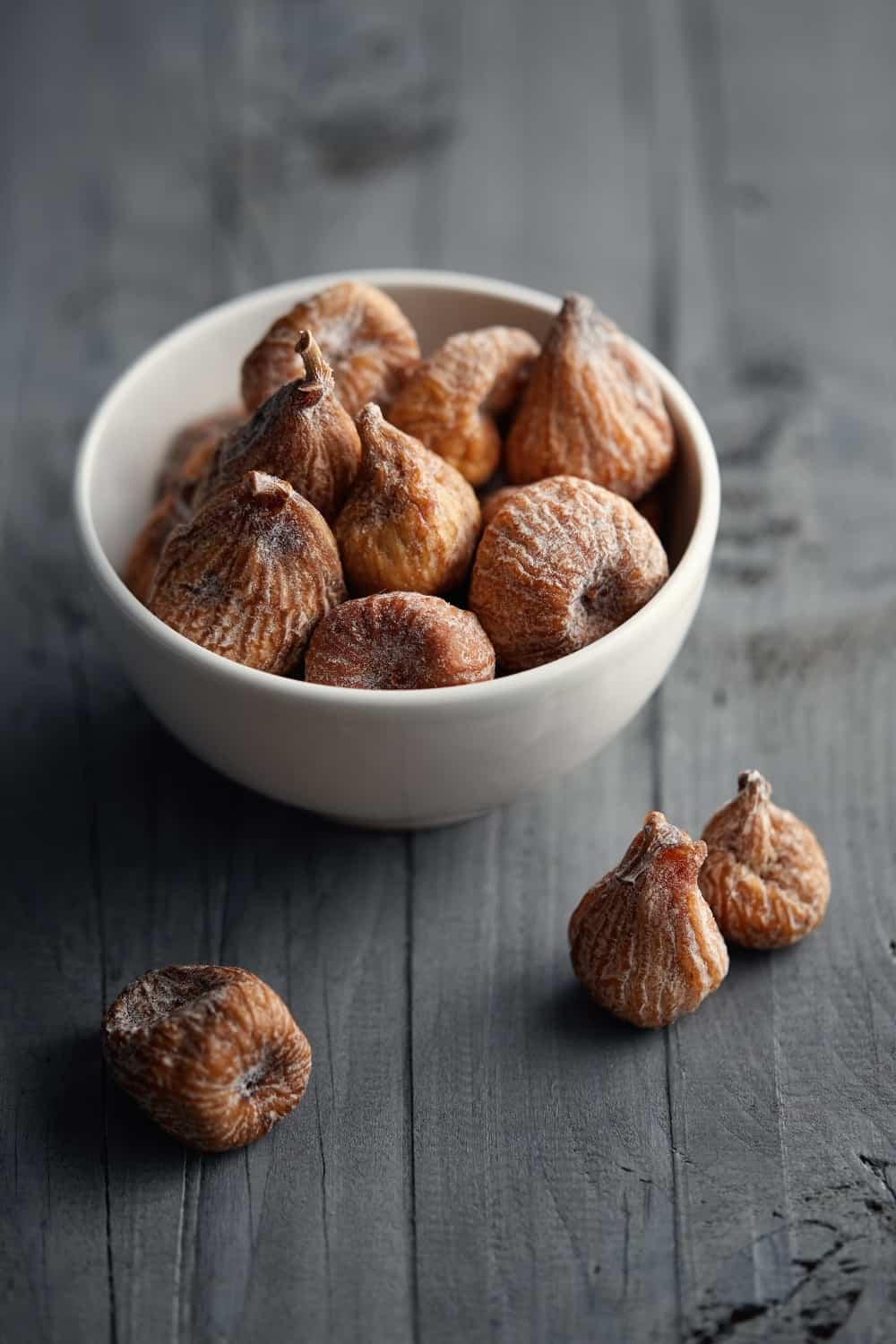 Dried figs in a bowl, on a grey surface