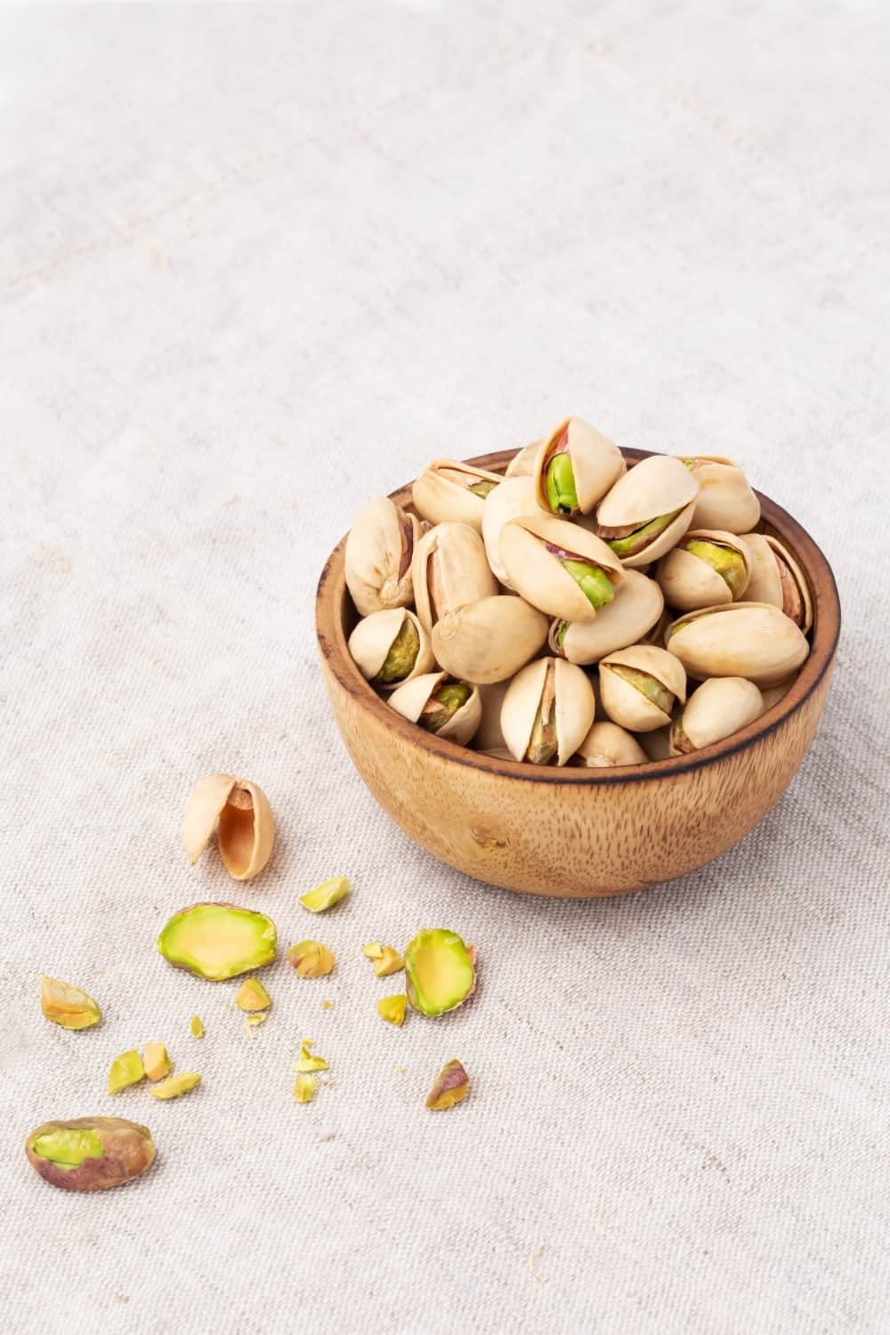 Pistachio in wooden bowl on linen table cloth background with copy space