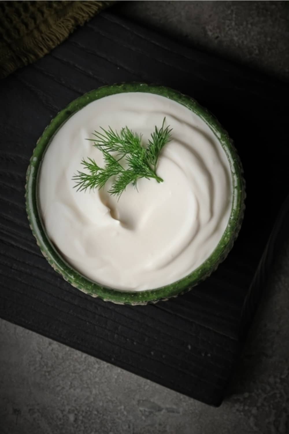 Crema agria en un cuenco verde sobre la mesa