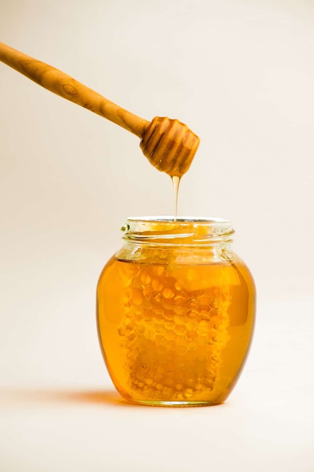 photo of a jar of honey with honeycomb inside
