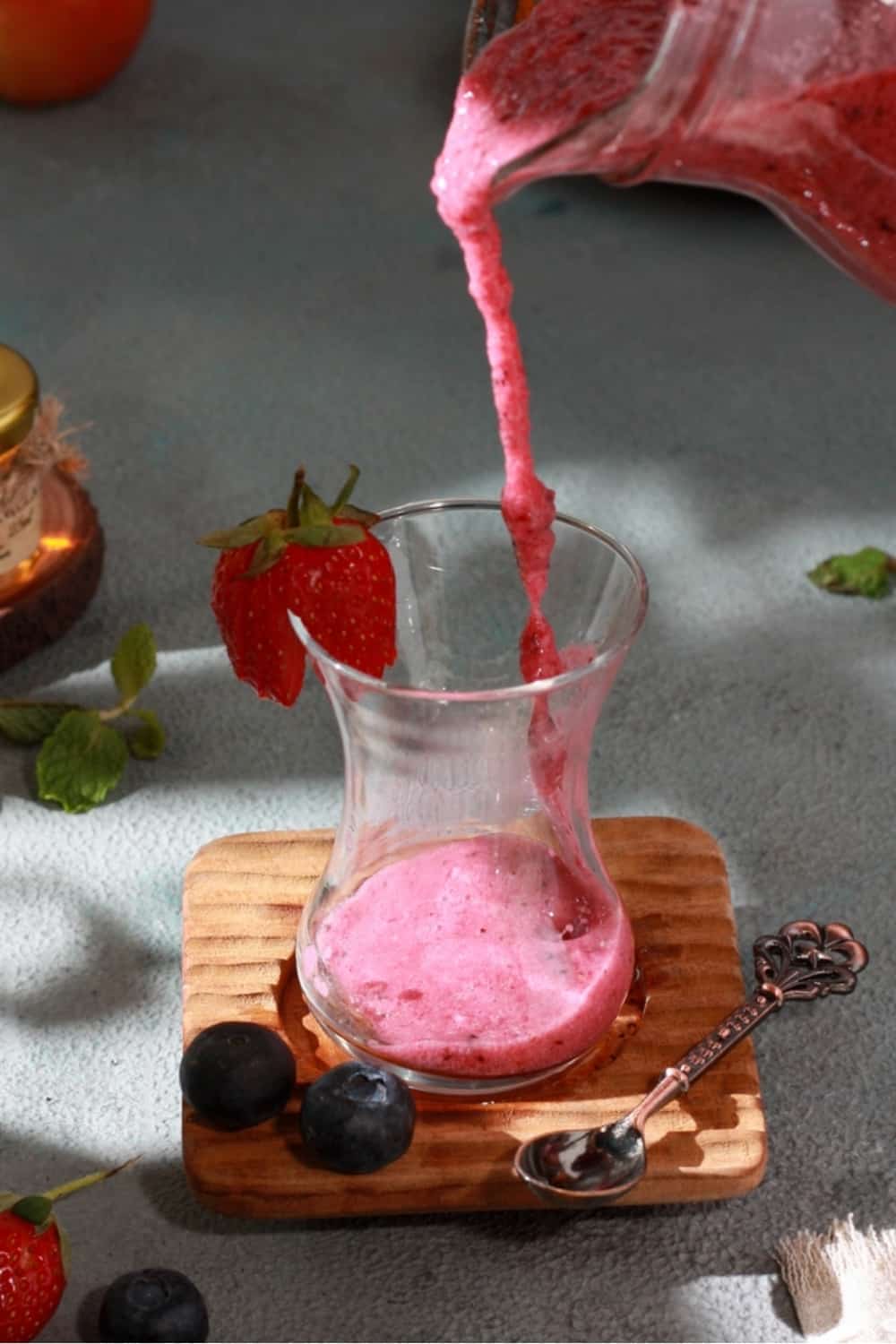 pouring a pink smoothie in a glass