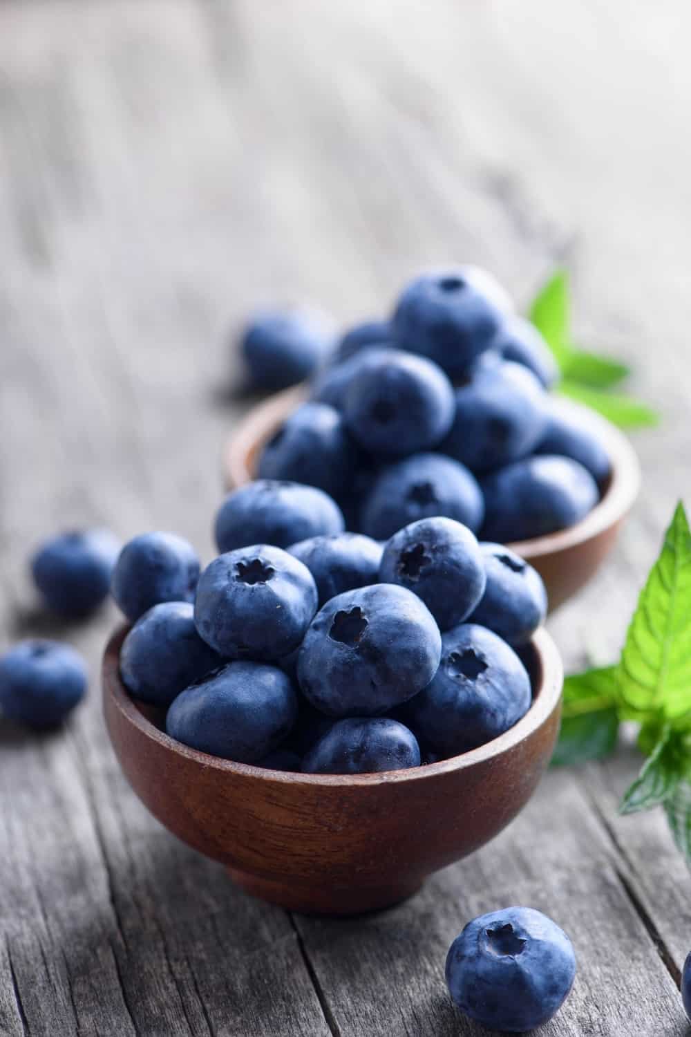 Schale mit frischen Blaubeeren auf rustikalem Holztisch