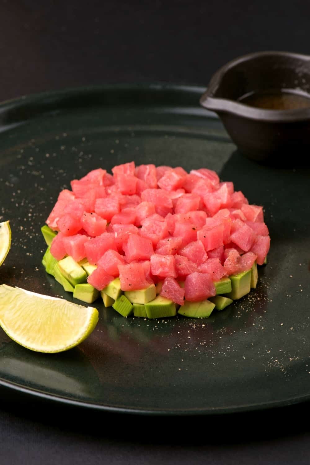 Tartar von frischem rohem Thunfisch mit Gewürzen in Nahaufnahme auf einem Teller.